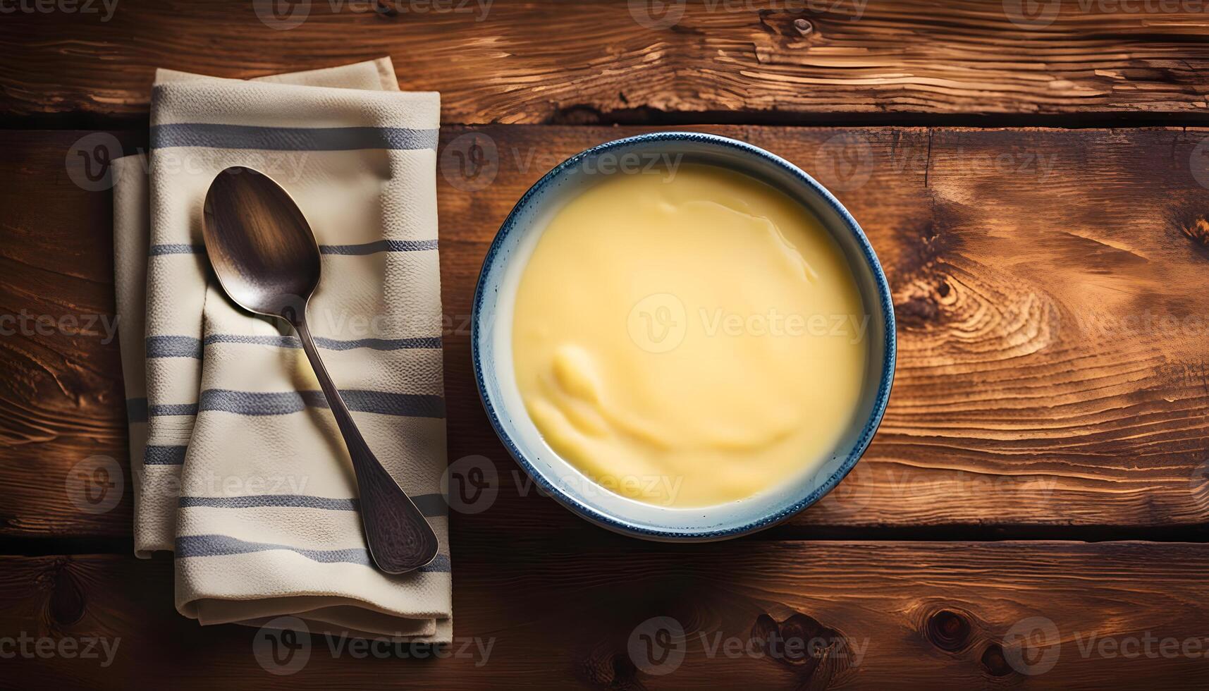 Bowl of homemade vanilla custard on wooden table photo