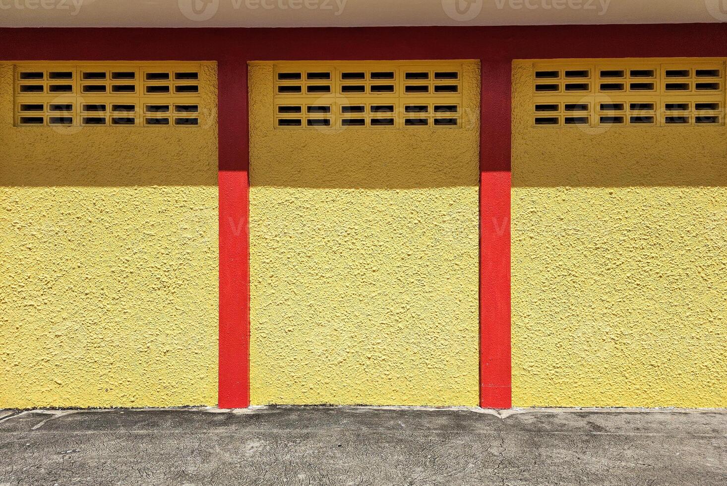 Yellow Wall and Red Poles with Concrete Floor. photo