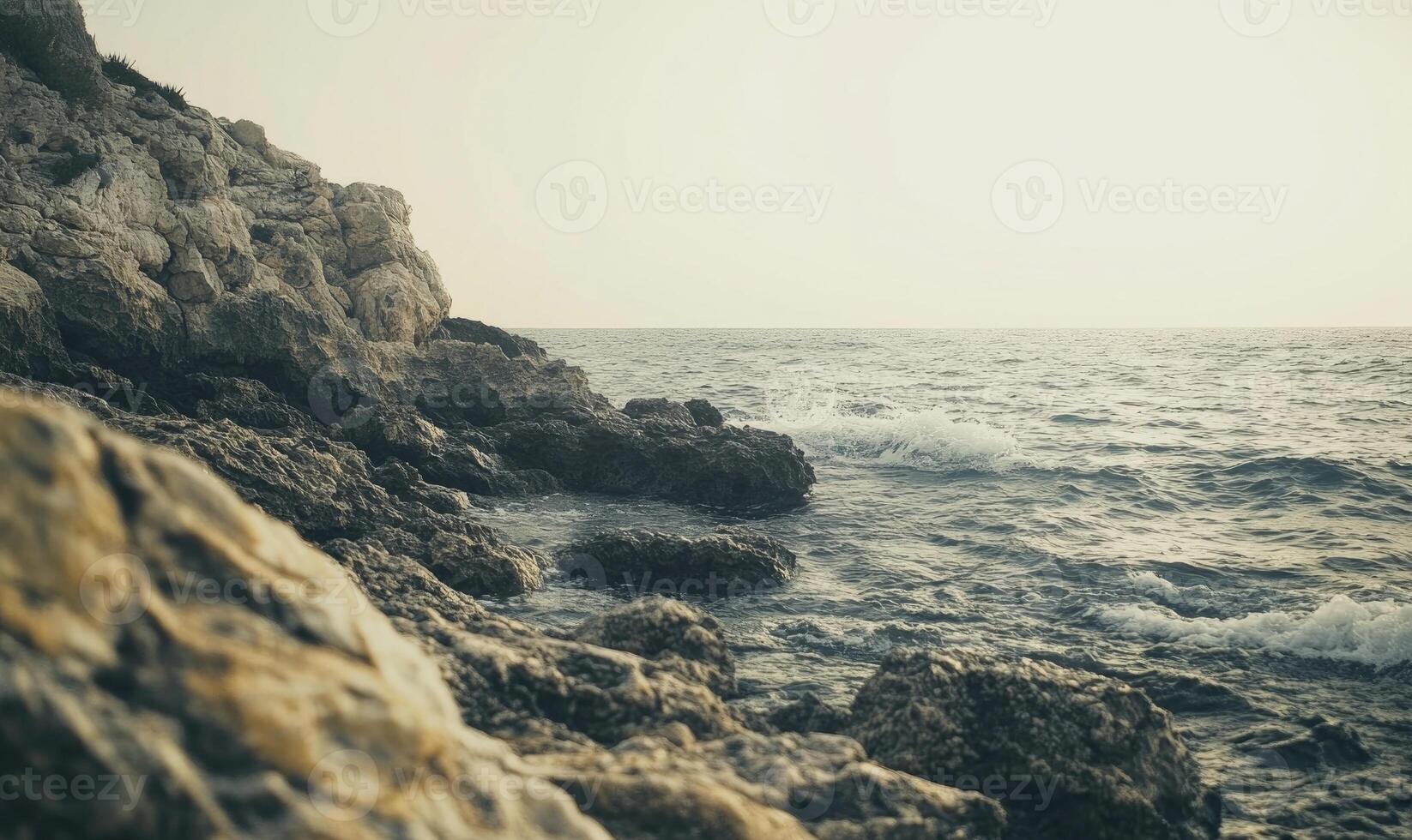 A rocky shoreline with a calm ocean in the background photo