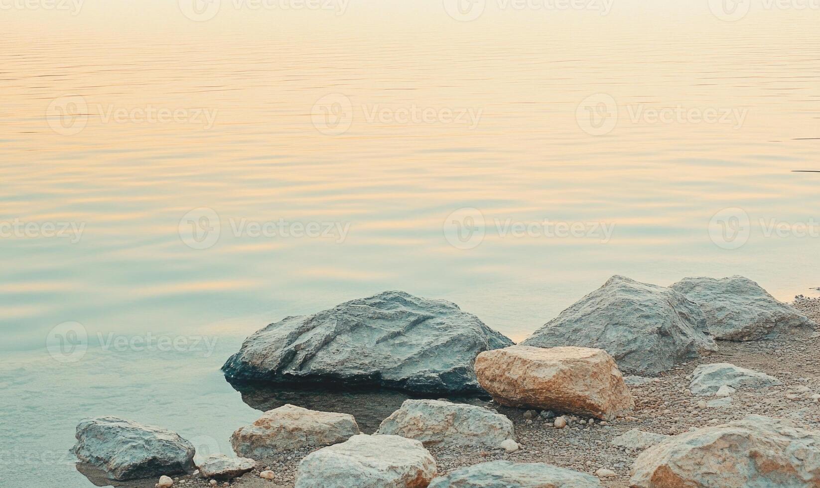 A rock is sitting on the shore of a lake photo