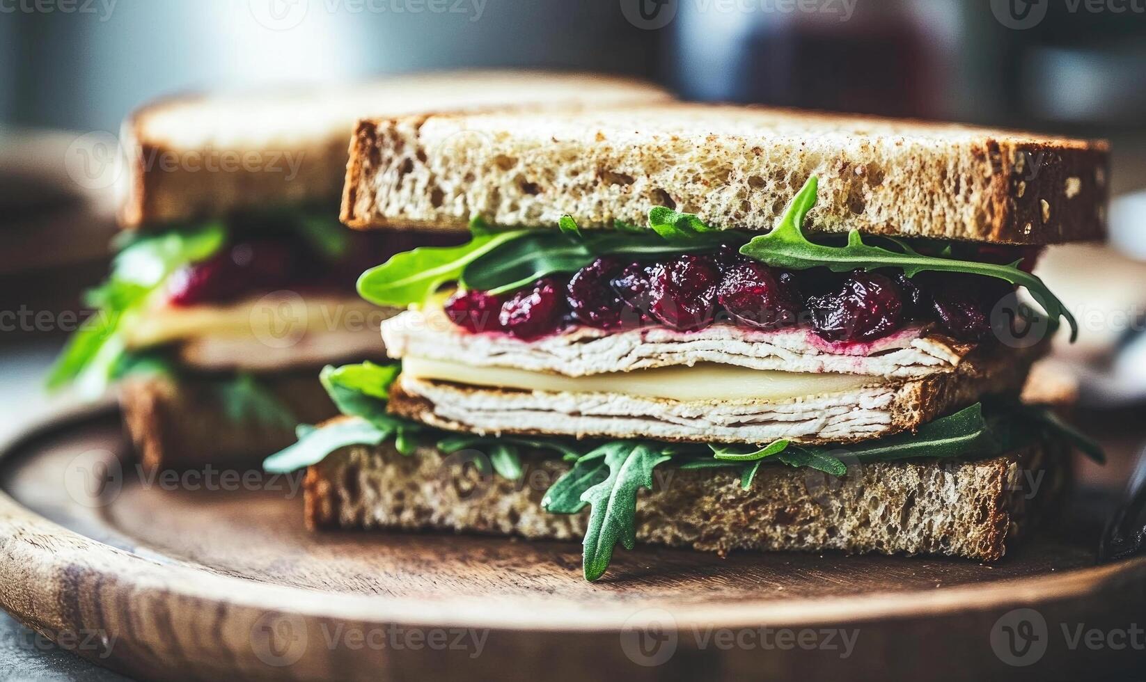 A sandwich with turkey and cranberry sauce is on a wooden plate photo