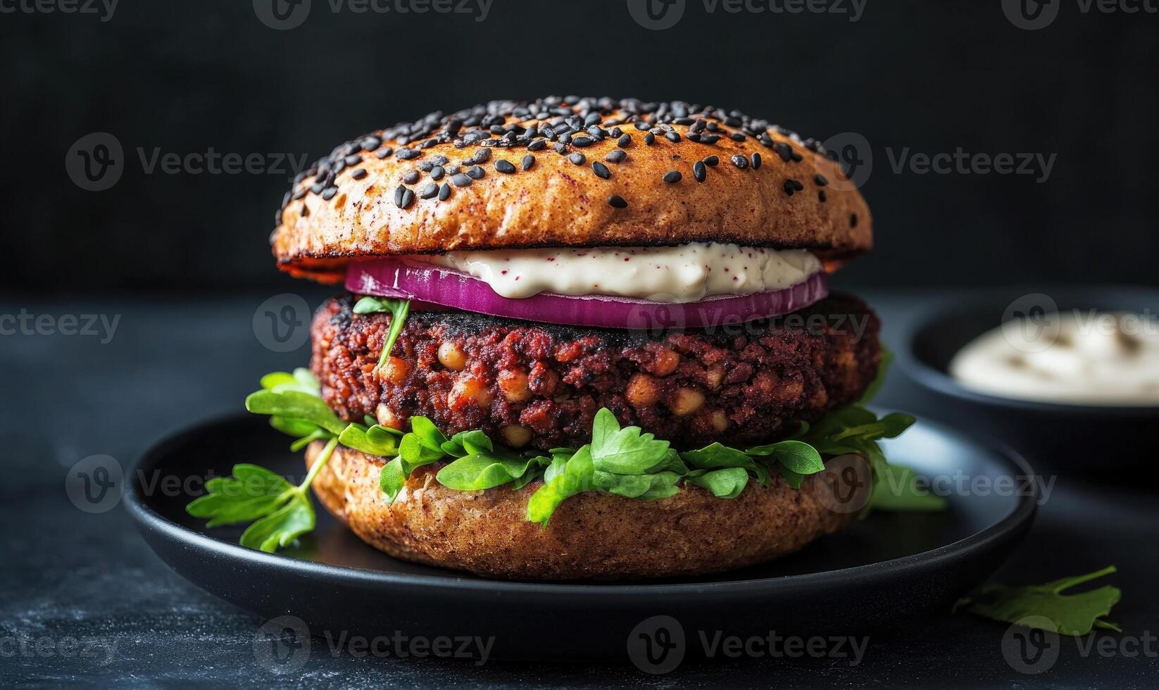 A burger with onions and a sauce on a black plate photo