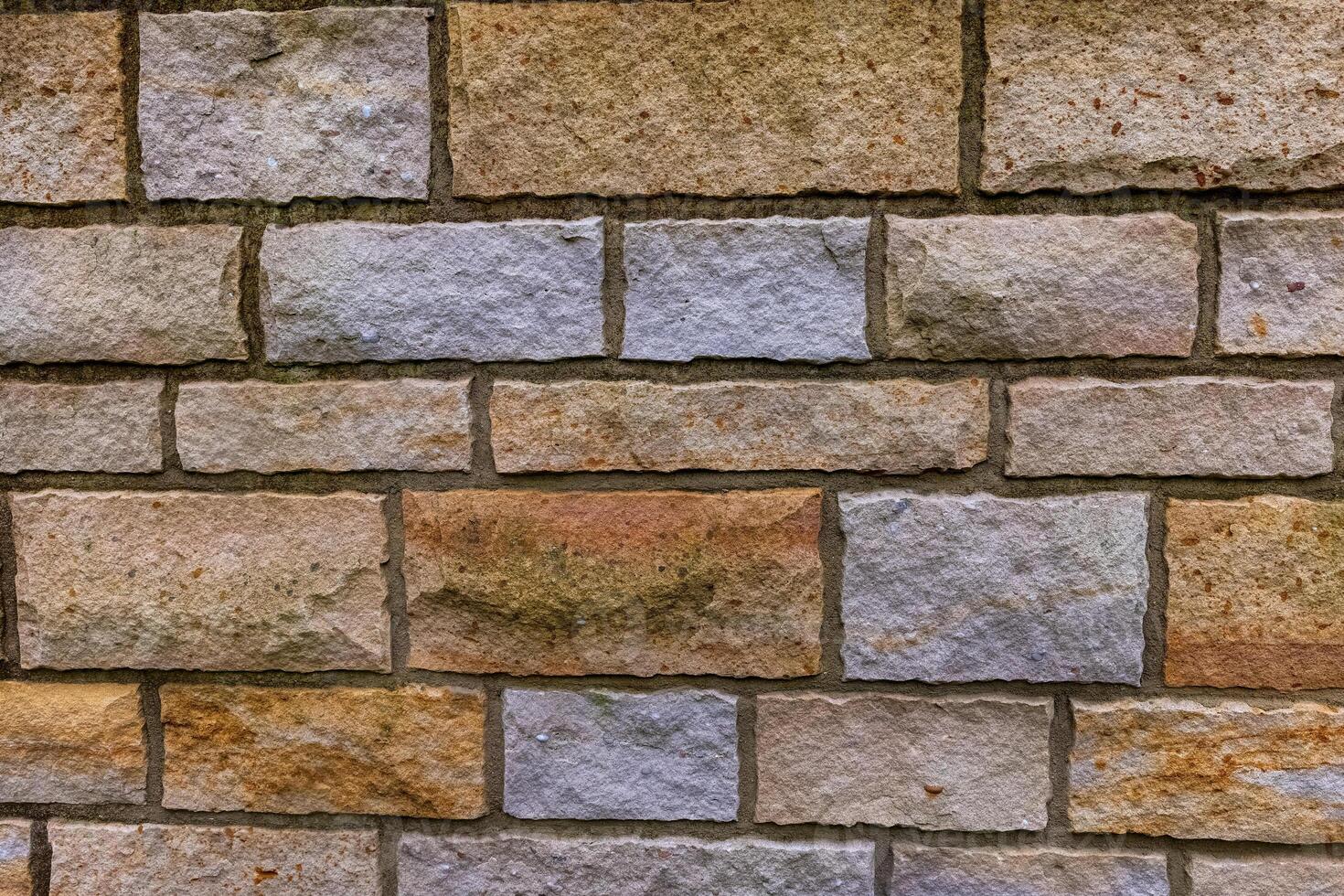 A close-up of a rough, textured stone wall with a variety of colors and sizes photo