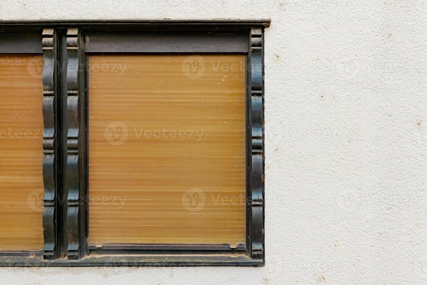 A window with wooden blinds is closed and framed in black trim photo