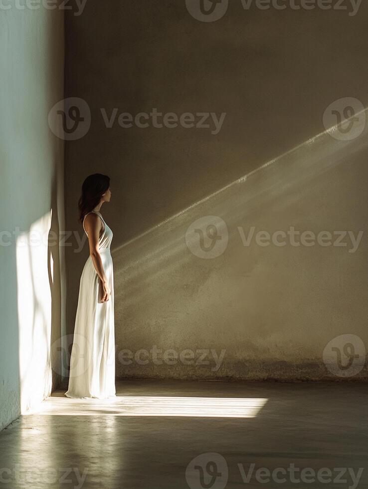 A woman in a white dress stands in an empty room photo