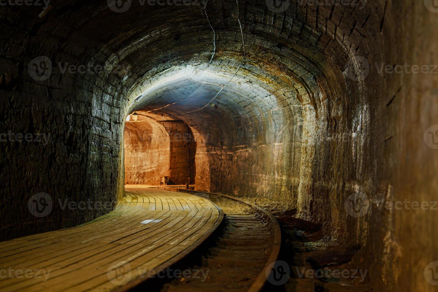This captivating underground arched brick tunnel features a sturdy wooden walkway stretching into the distance, illuminated by bright lights, creating a mysterious and inviting atmosphere cooper mine photo