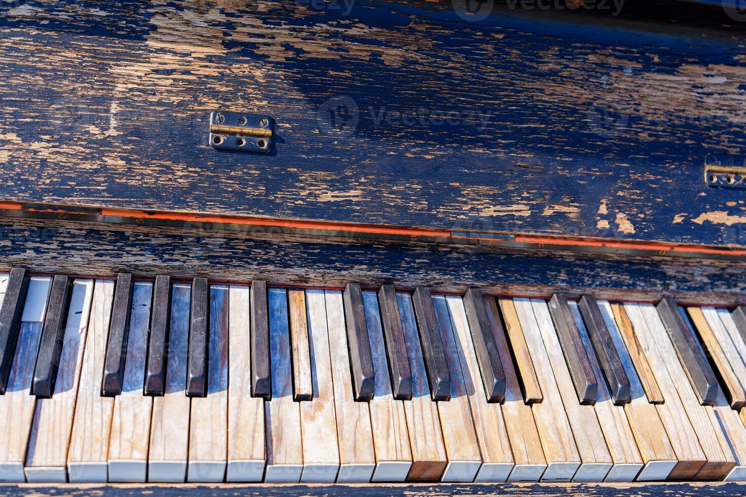The image features piano keys with peeling paint against a black wooden background. The colorful keys are arranged in a staggered pattern, creating a unique and charming visual appeal. photo