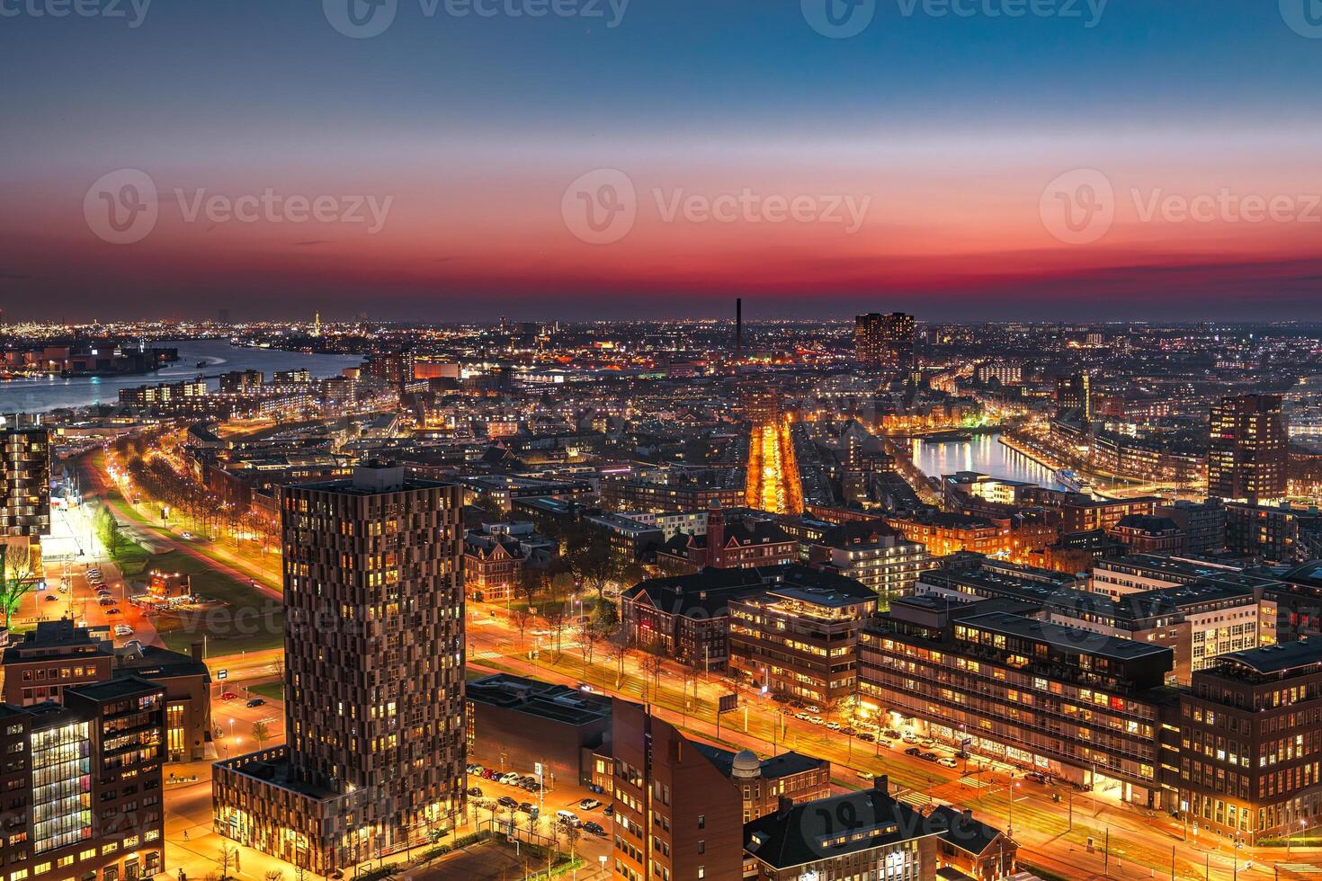 A stunning cityscape showcases modern skyscrapers along a river, illuminated by the warm glow of the setting sun, creating a vibrant and energetic atmosphere in the heart of the city. photo