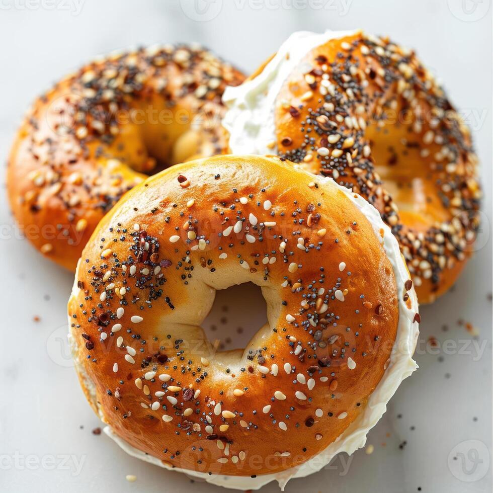 Close-up of two fresh baked bagels with a spread of cream cheese and sprinkles of poppy seeds. photo