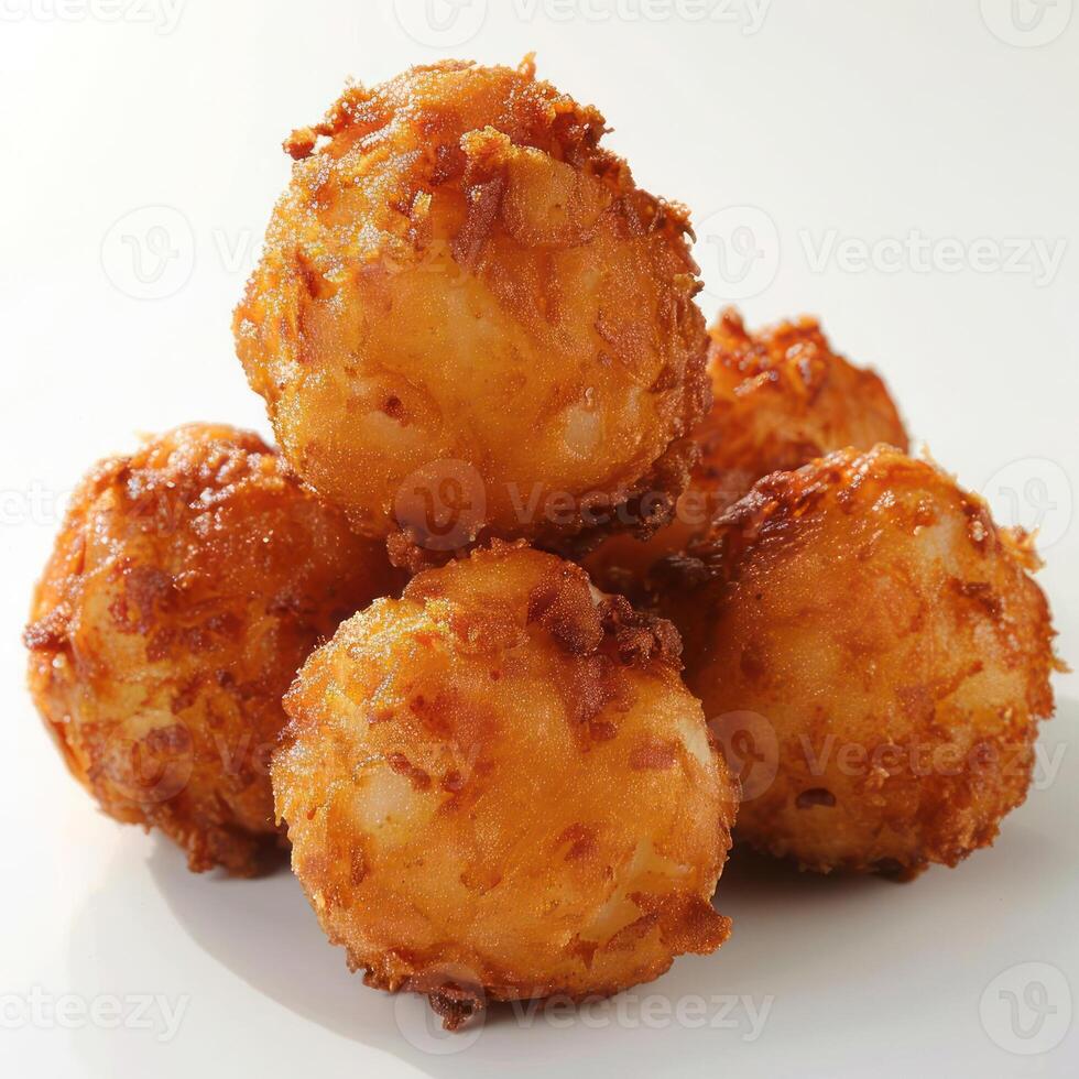 Three golden brown fried balls of food on a white surface. photo