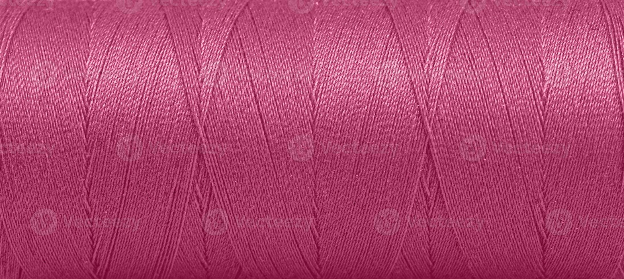 Texture of threads in a spool of pink color on a white background photo
