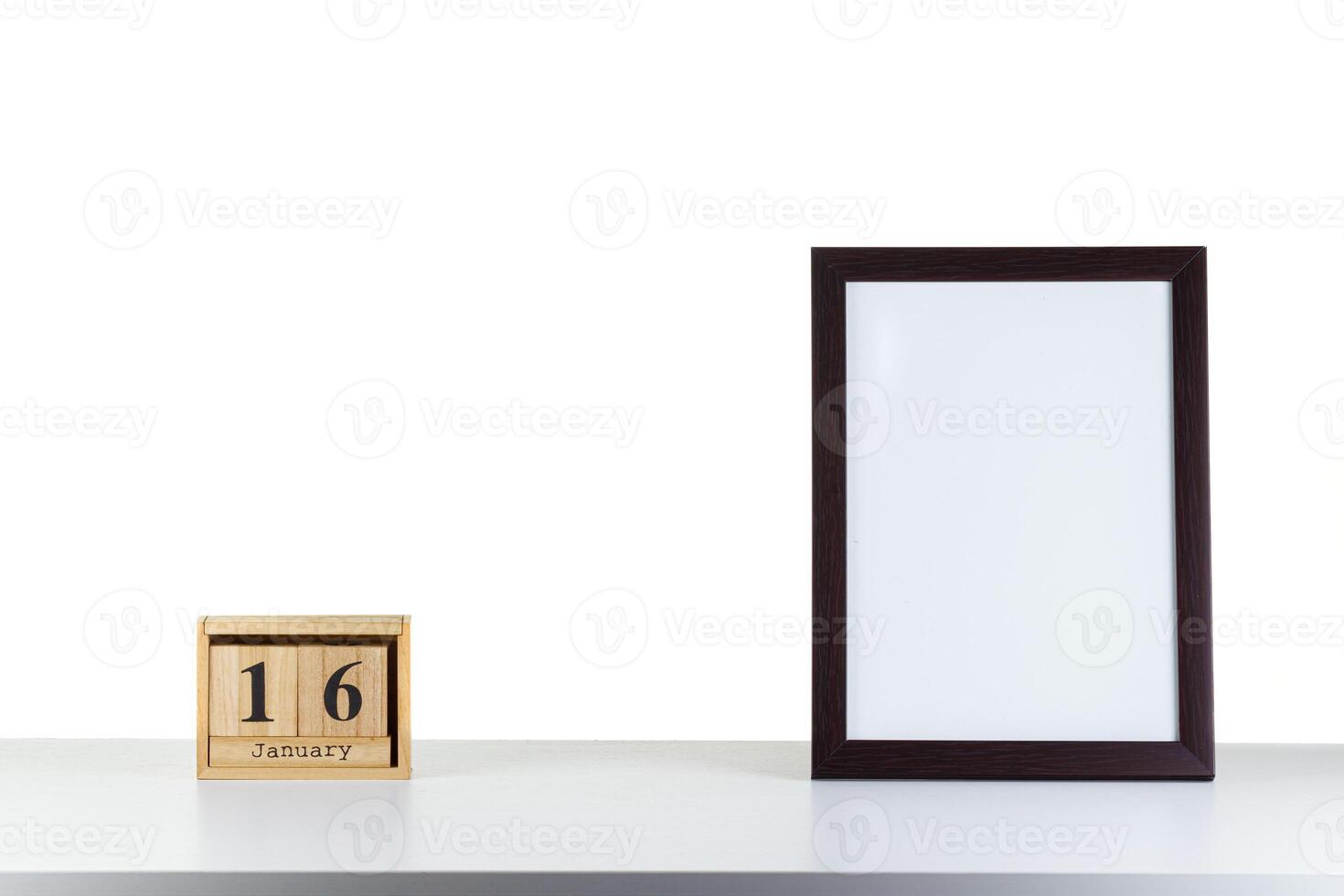 Wooden calendar 16 January with frame for photo on white table and background