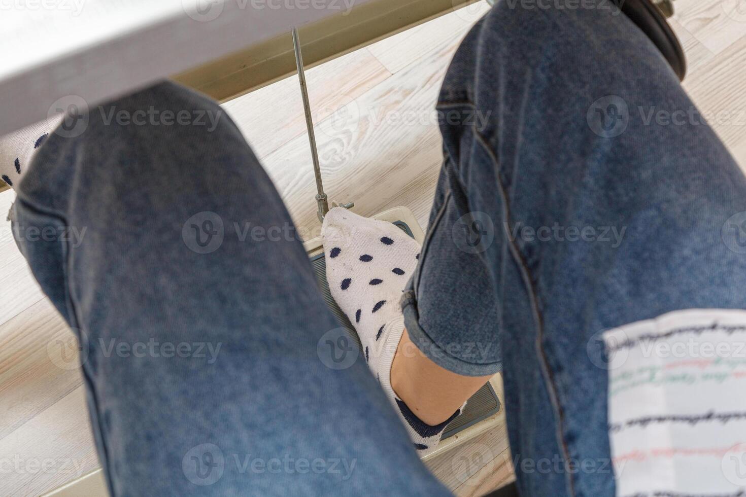 Female feet on the pedal of a sewing machine, motor photo