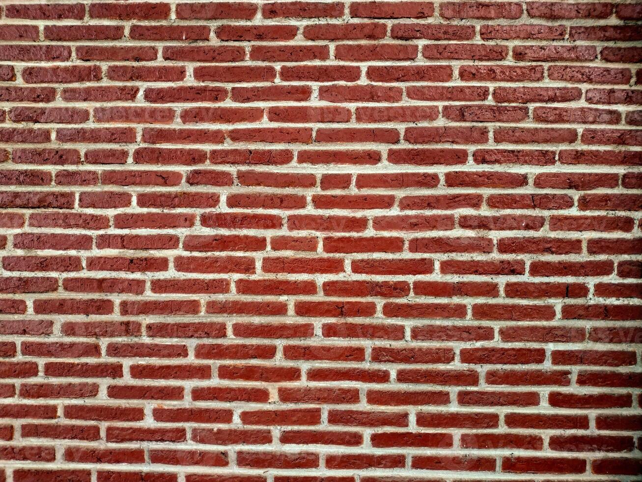 A textured red brick wall with a classic horizontal pattern, showcasing the rustic charm and architectural simplicity of traditional masonry work. photo