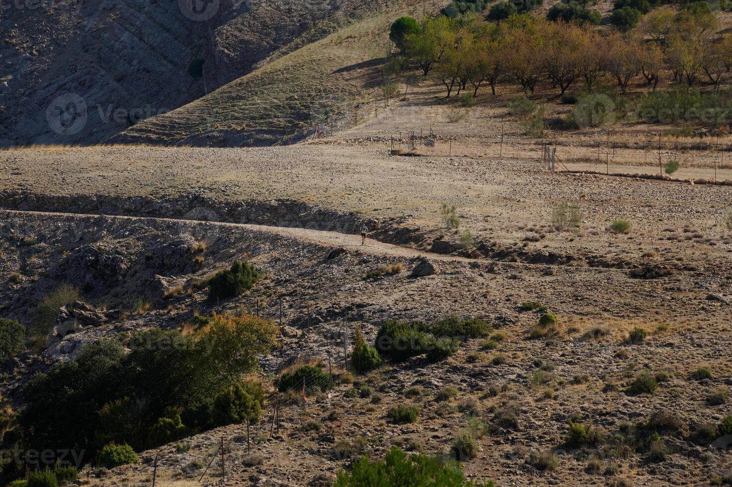 Vast rocky landscape with distant runner among rugged terrain photo