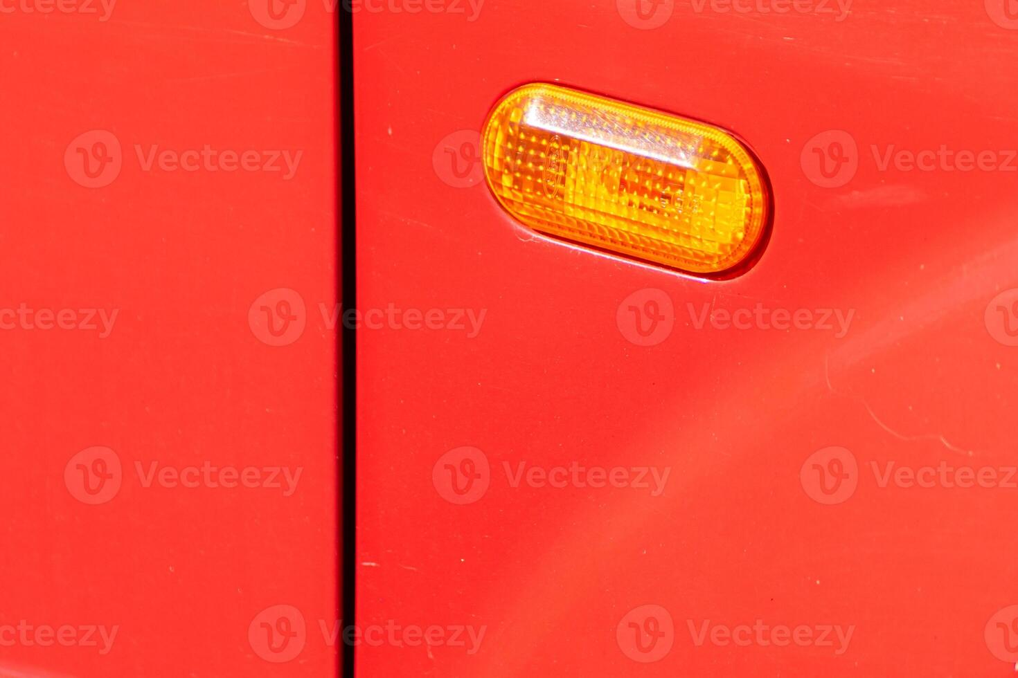 Driver side headlights on a car. close-up view of the front side flasher of a red car photo