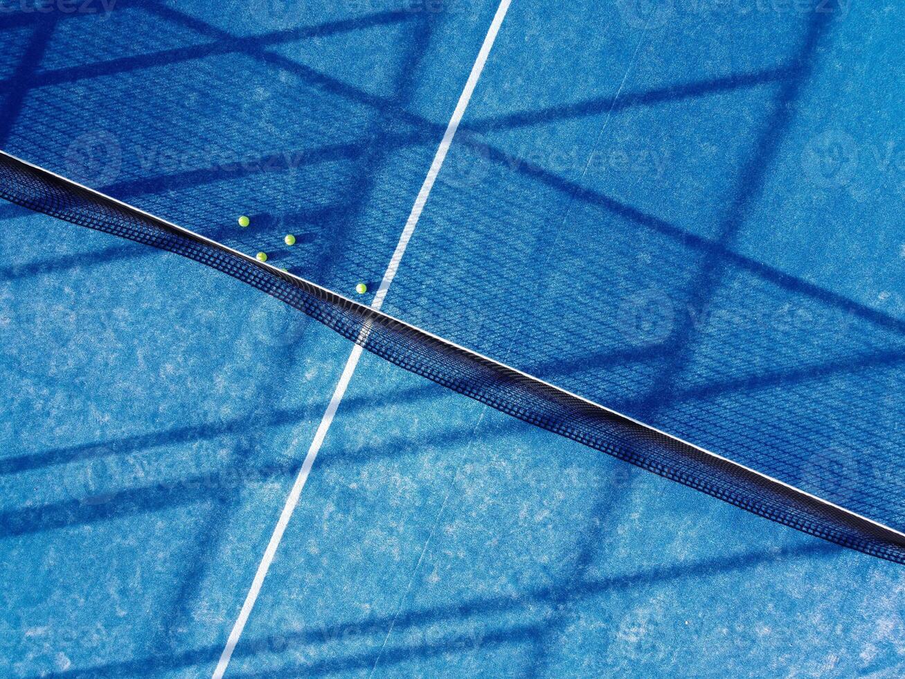aerial top image of five balls near the net on a blue artificial grass paddle tennis court photo