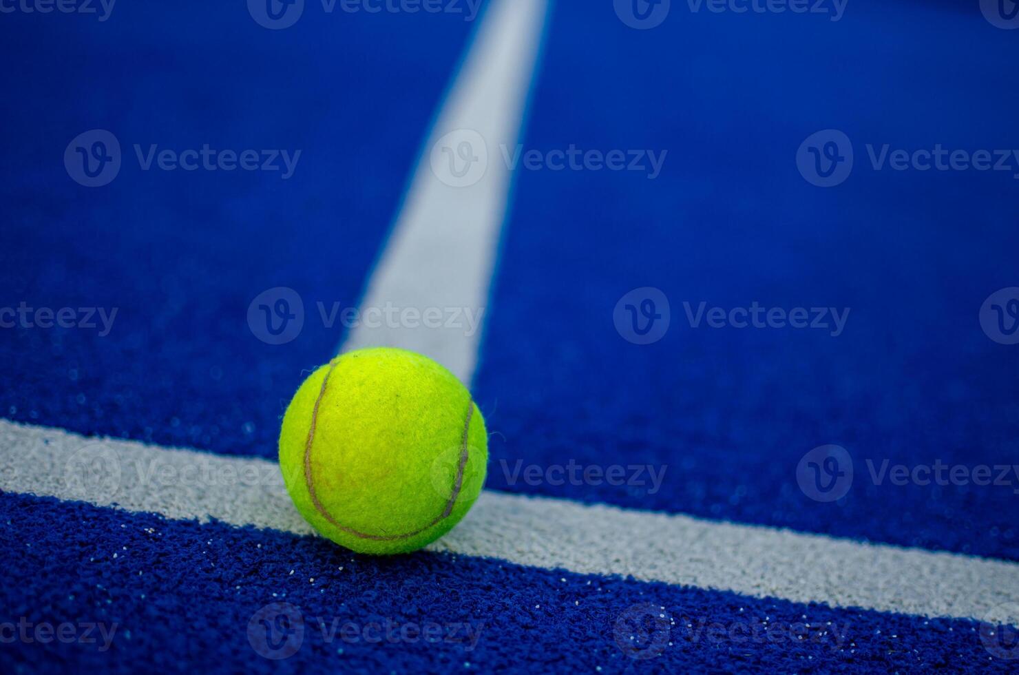 selective focus of a ball on the white line of a blue paddle tennis court photo