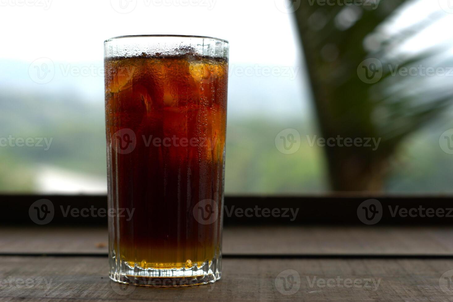 A glass of cold ice tea on wooden table with copy space area photo