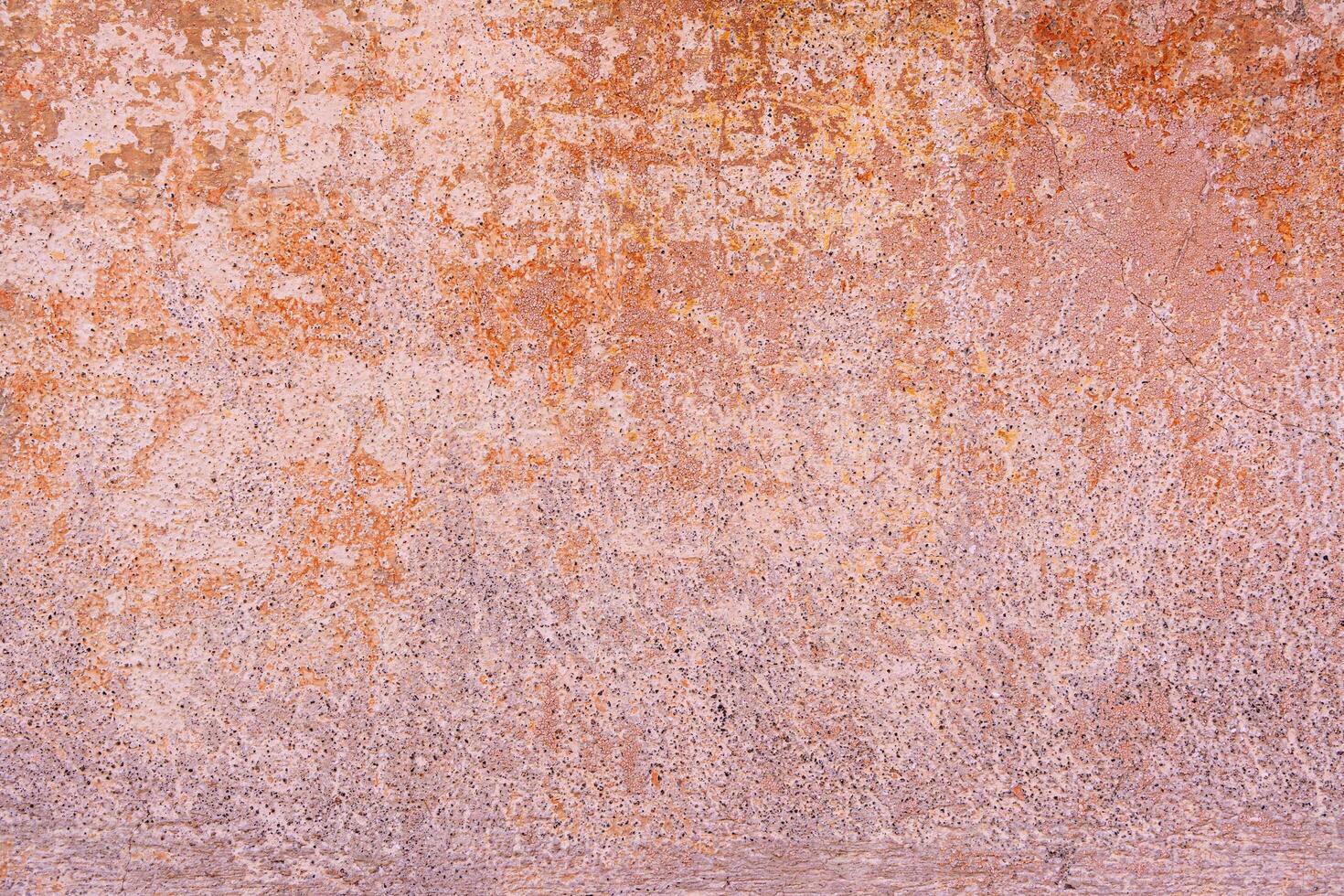 Textured surface with shades of pink, orange, and brown, appearing weathered. photo