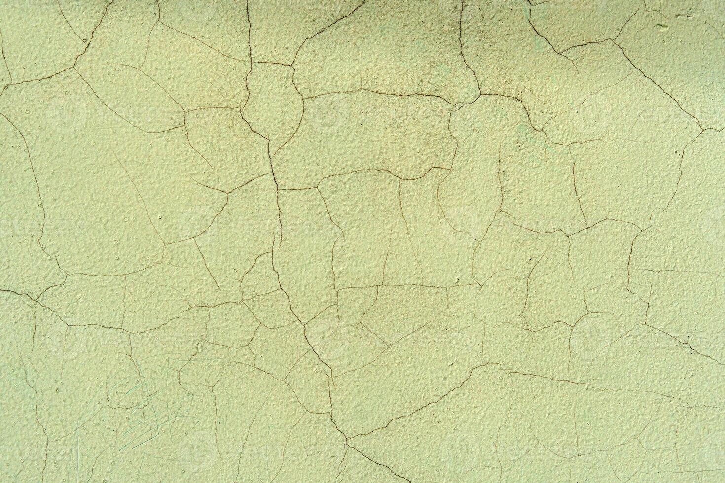 Wall with cracks in green plaster. The wall looks old and worn out photo