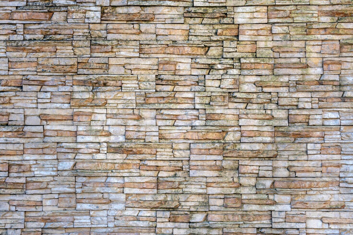 A wall made of stone blocks with a brownish color. The wall is very old and has a rough texture photo