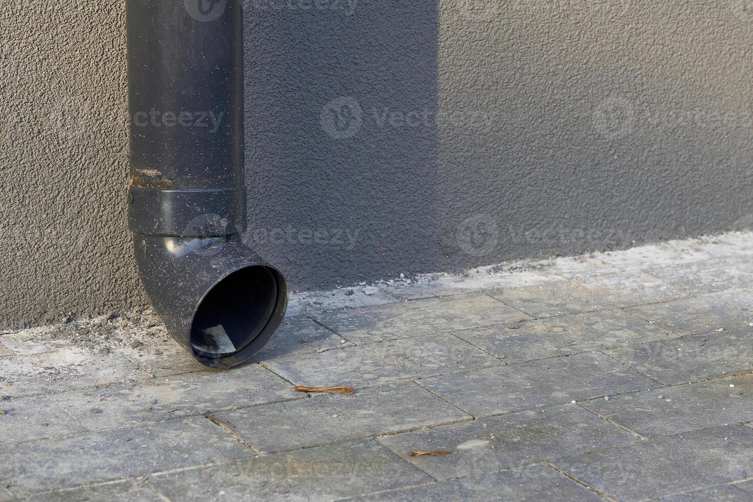 Rain runoff.New plastic drain pipe on a gray plastered wall photo