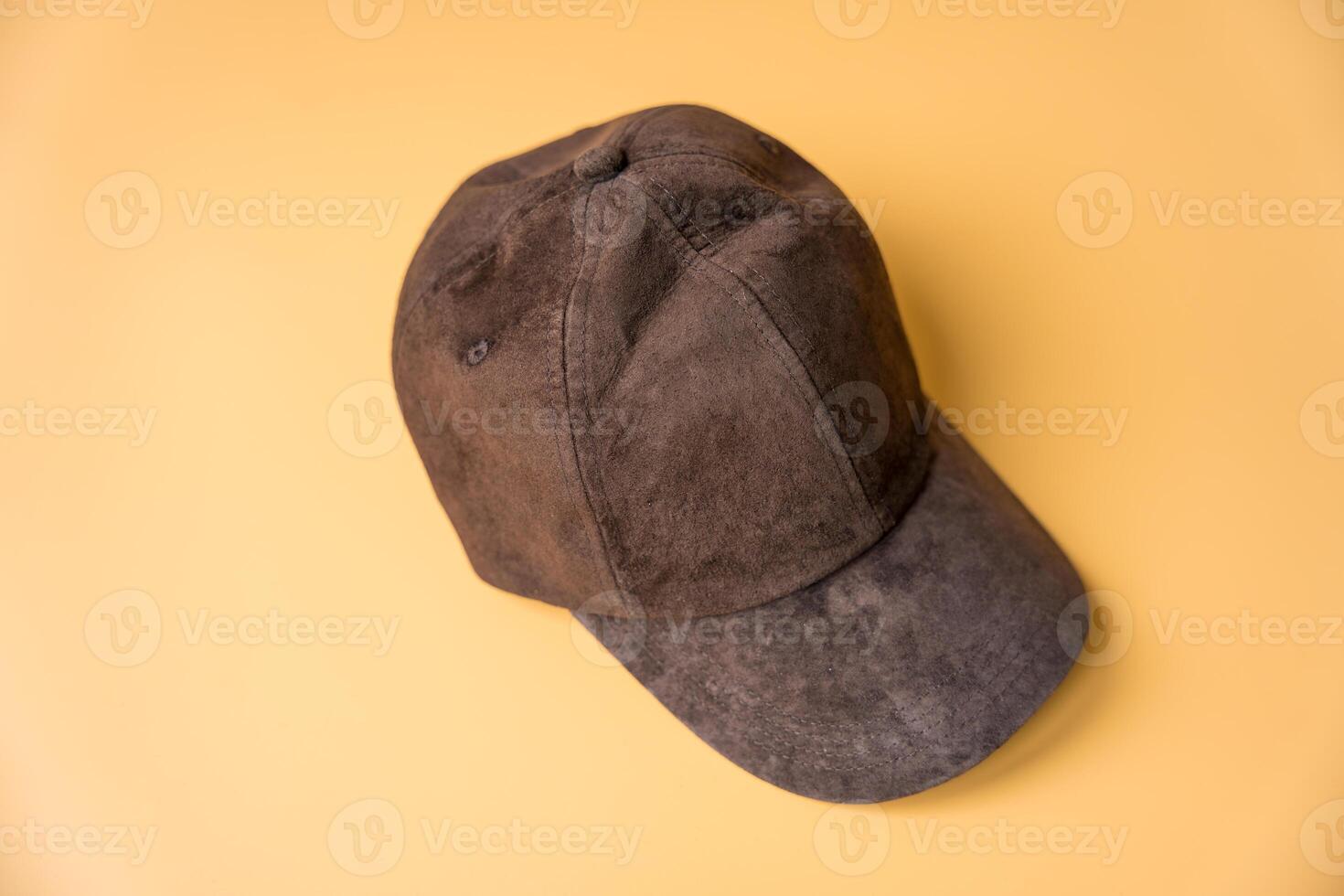 Womens dark brown baseball cap made of genuine suede on a peach fuzz background. photo