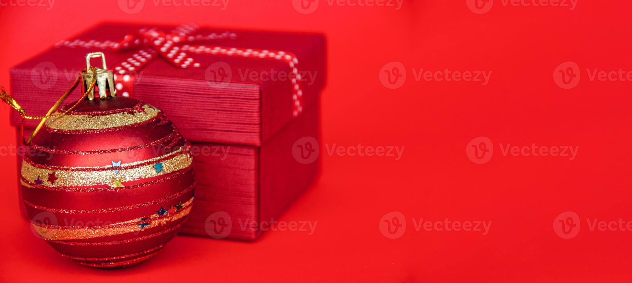 Presents and Christmas ball on red cover background with customizable space for text. Copy space and Christmas celebration concept. photo