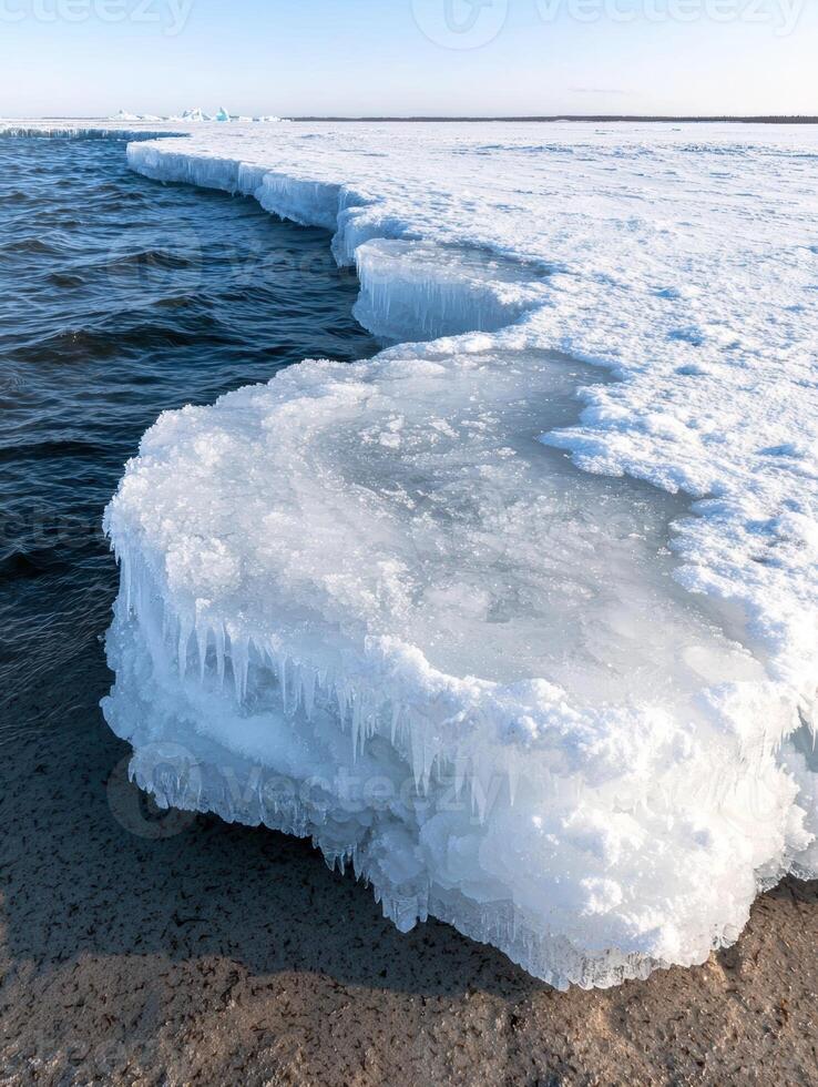 Icy shoreline with frozen waves and icicles photo