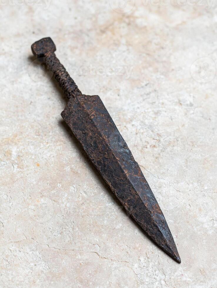 Rusty old metal tool or weapon on a concrete surface photo