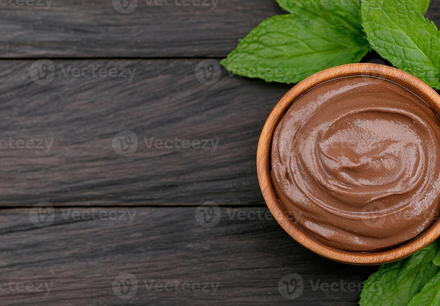Chocolate spread in a wooden bowl with fresh mint leaves photo