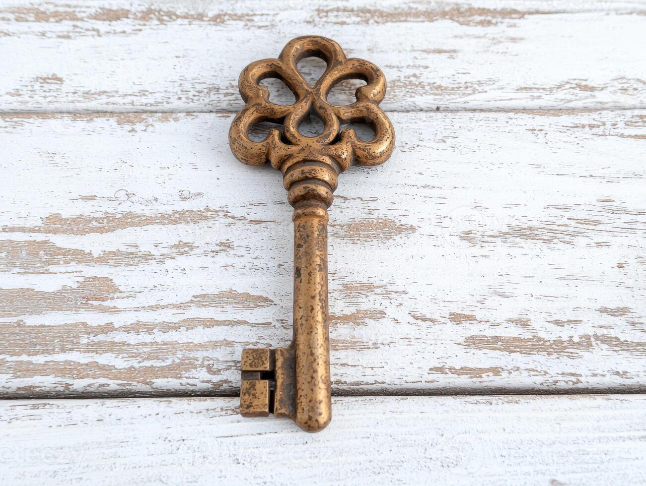Antique ornate metal key on weathered wooden background photo