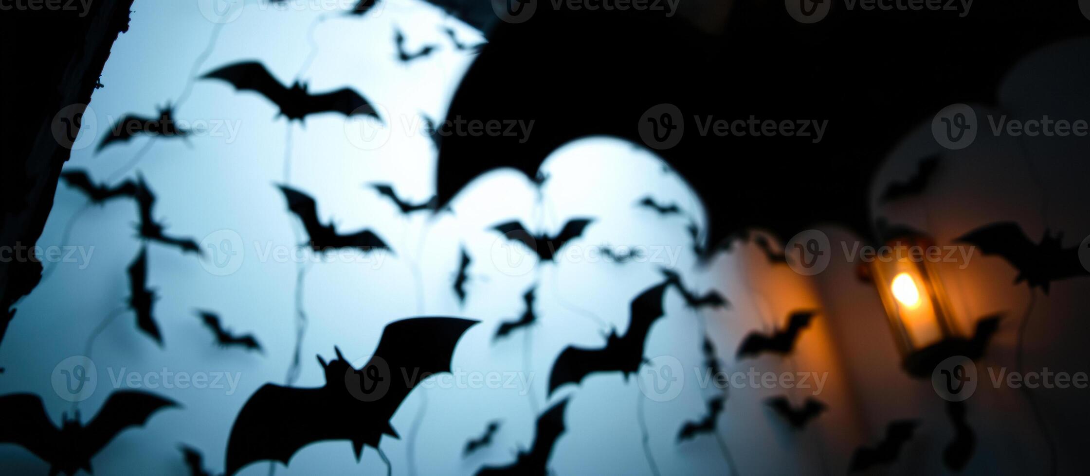paper bats adorn a wall with a lantern's warm glow photo