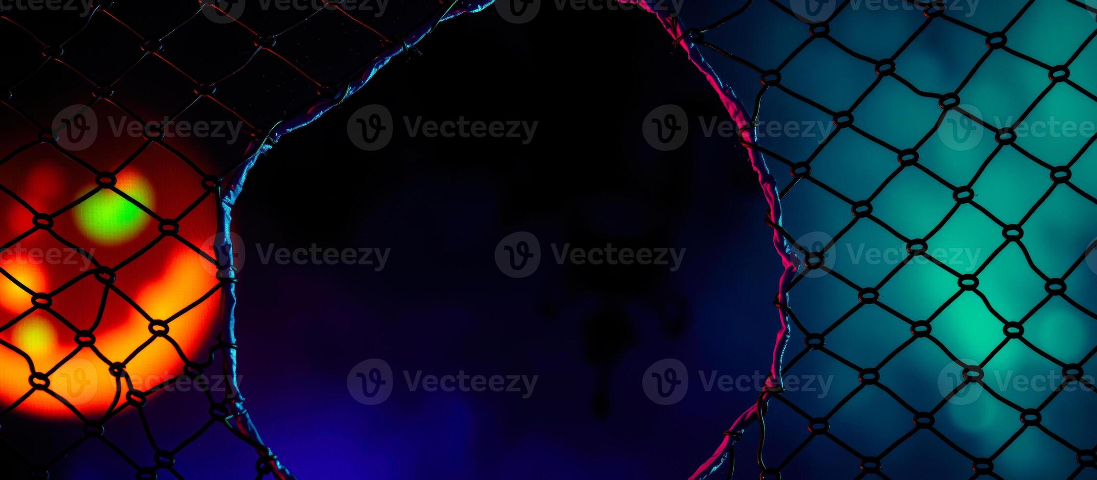 torn chain-link fence glows with neon light photo
