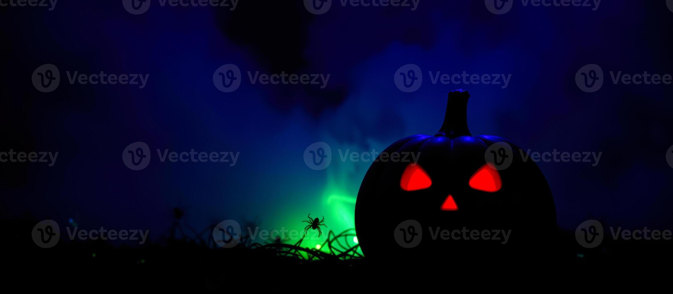 carved pumpkin with glowing red eyes sits a foggy field photo