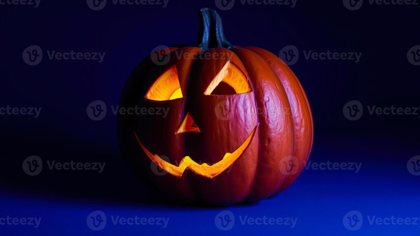 lit carved pumpkin on a dark blue background photo