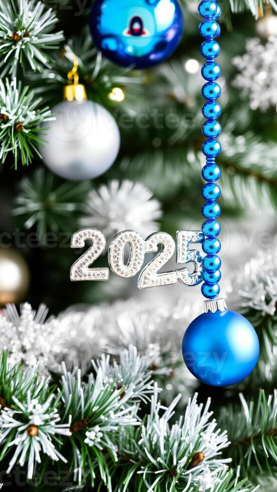 2025 ornament hangs on a frosted pine tree photo
