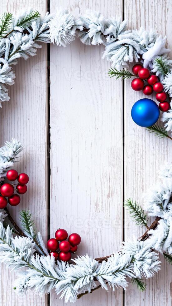 snowy pine garland with red blue ornaments on white wood photo