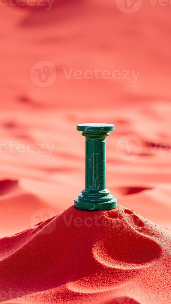 green marble pillar resting on a red sand dune photo