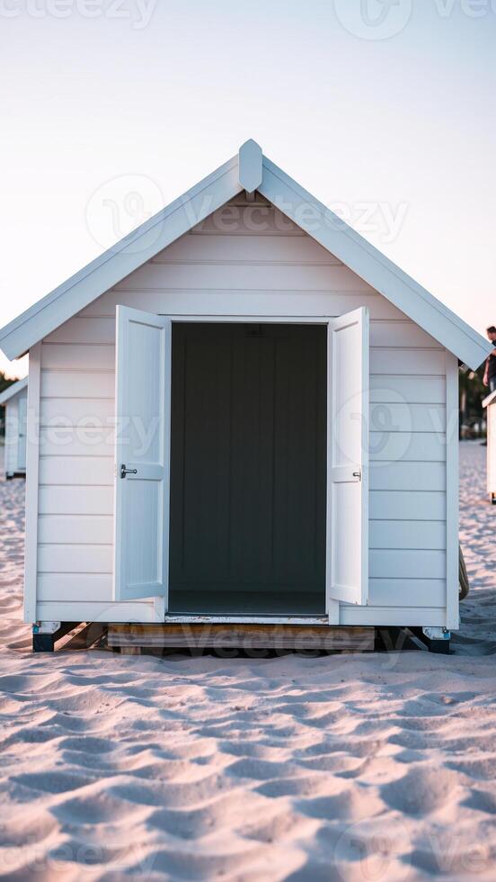 white beach house with an open door stands on a sandy beach photo