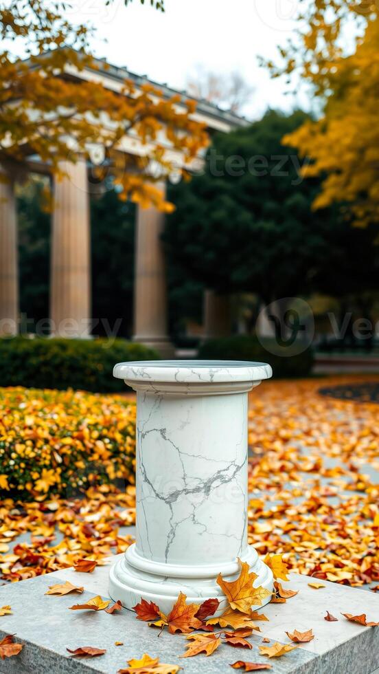 white marble column surrounded by autumn leaves photo