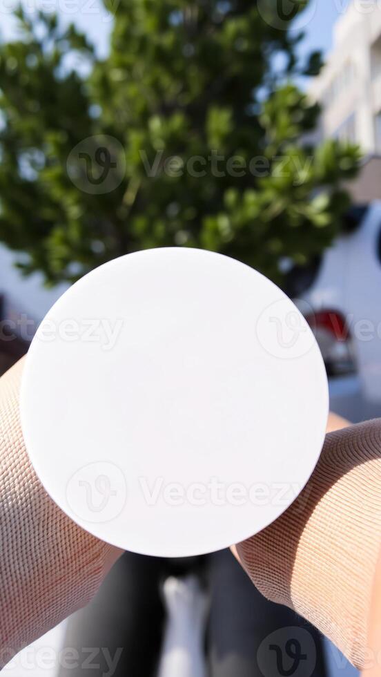 white circular object held against a blurry green background photo