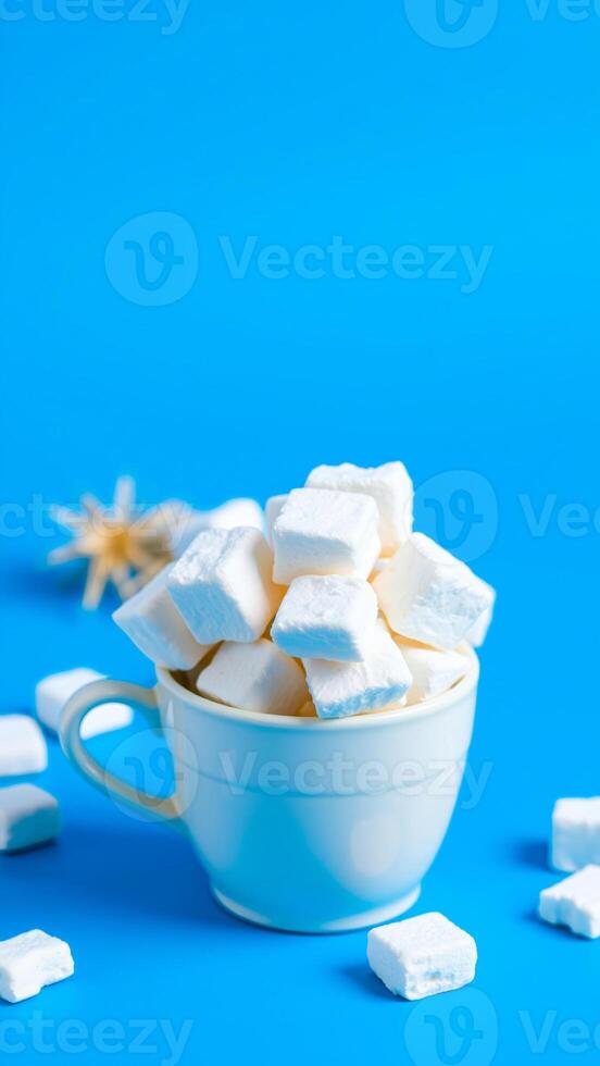 white mug filled with marshmallows on a blue background photo