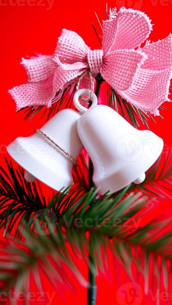 two white bells hang from a pink bow on a green branch photo