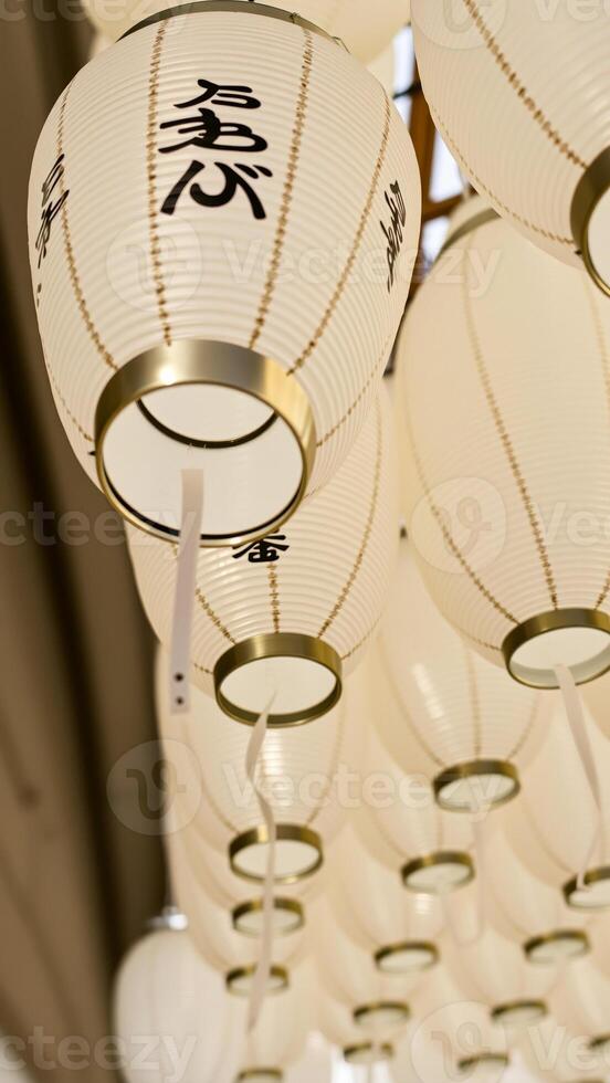white paper lanterns with black calligraphy hang from the ceiling photo