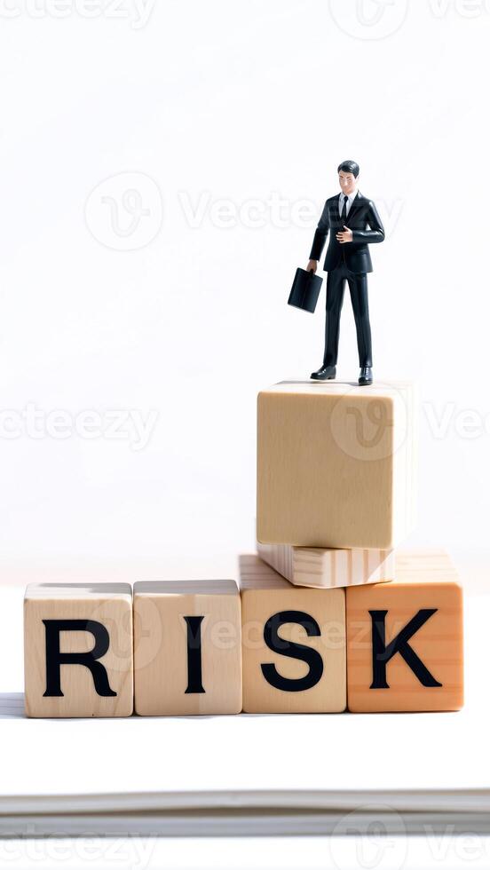 businessman standing on a stack blocks spelling 'risk' photo