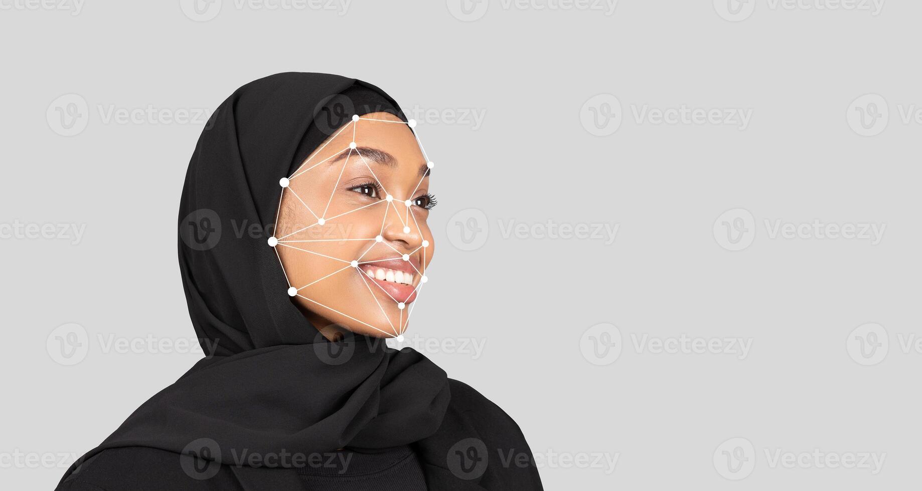 A young black woman in a black hijab smiles as facial recognition technology highlights key points on her face. This showcase occurs against a neutral gray background photo