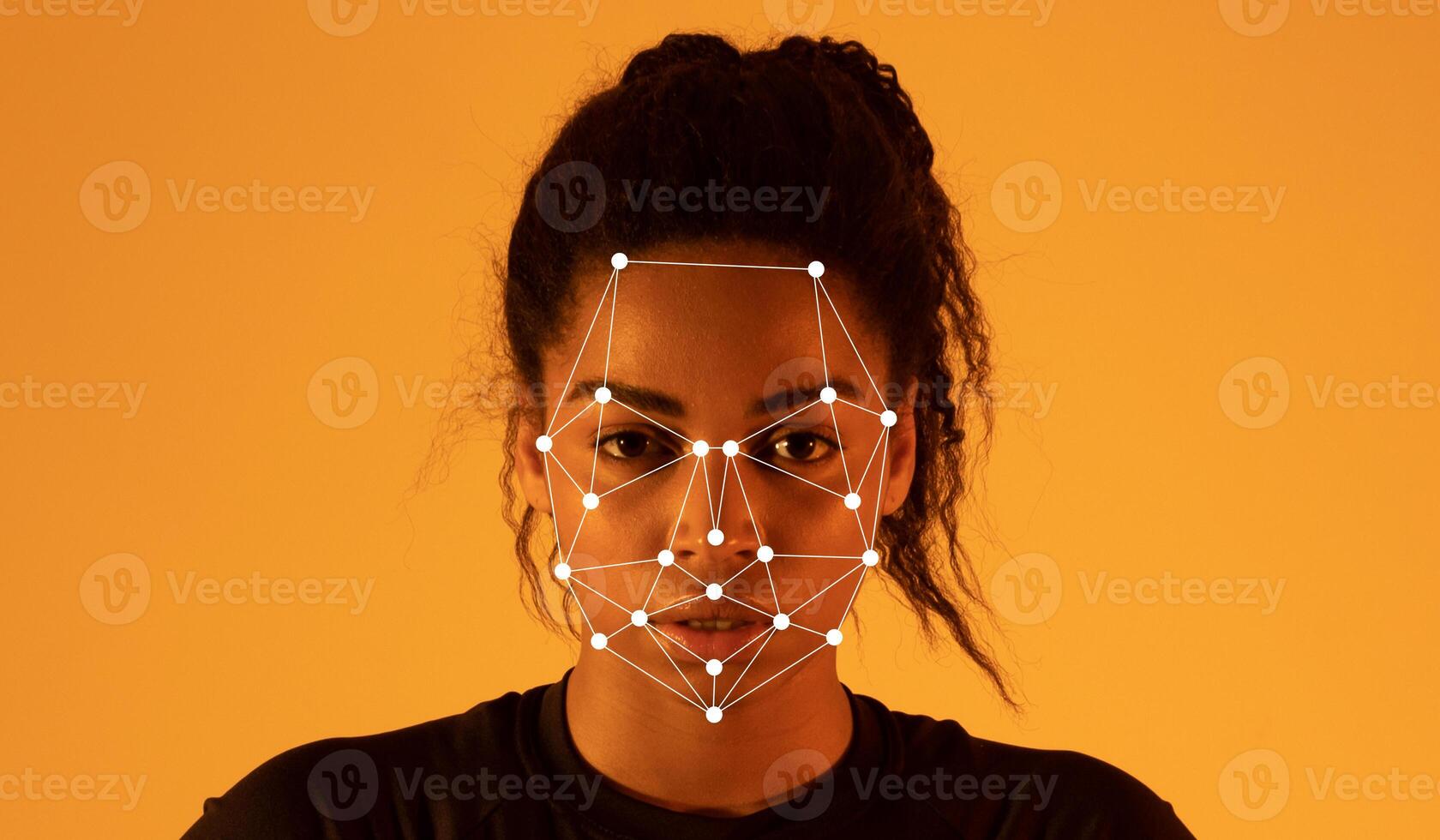 African American lady stands against a warm amber background while facial recognition markers are displayed on her face, highlighting facial features and expressions in a modern technological photo