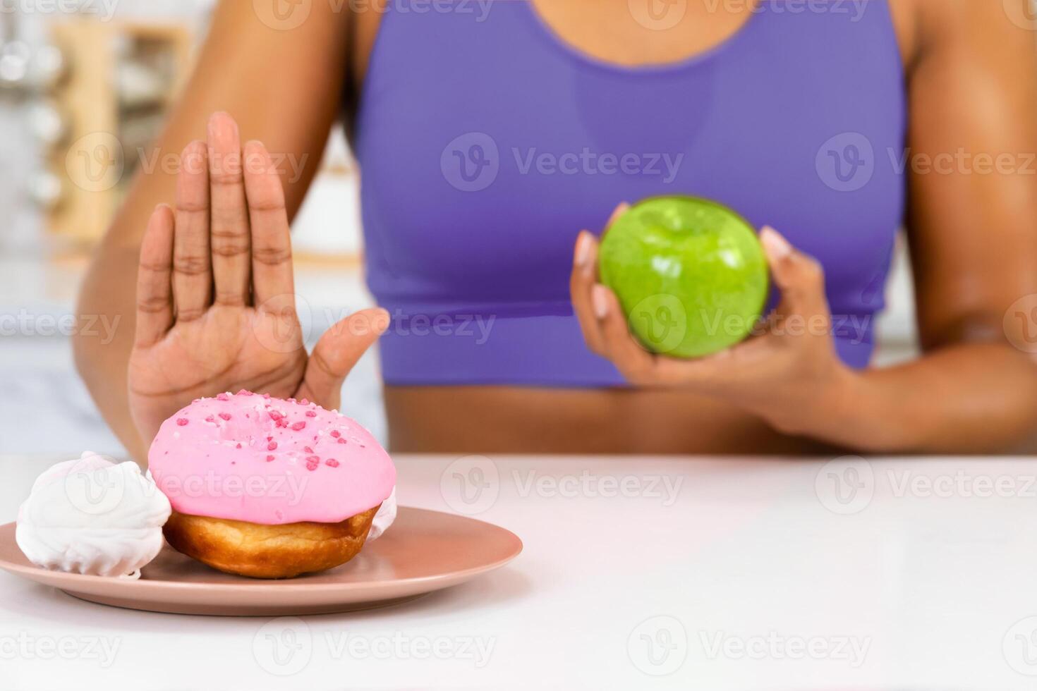 Right Choice Concept. Unrecognizable woman holding apple and making stop gesture to sweet donut, selective focus photo